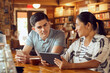 © SuperStock - Young man and woman sitting at counter in cafe bookstore looking at tablet