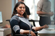 © SuperStock - Young woman sitting at computer in office looking to the camera smiling, co-workers having discussion around dry erase board in background