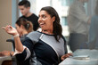 © SuperStock - Young woman at computer in office looking over shoulder pointing, co-workers having discussion around dry erase board in background
