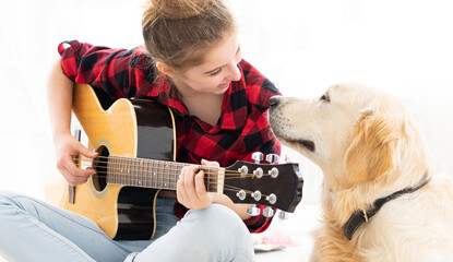 Wall Mural - Smiling teenage girl playing guitar to cute dog