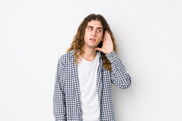 Wall Mural - Young long hair man posing isolated trying to listening a gossip.