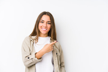 Wall Mural - Young caucasian woman  isolated smiling and pointing aside, showing something at blank space.