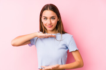 Wall Mural - Young caucasian woman wearing a ski clothes isolated holding something with both hands, product presentation.