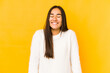 Young woman isolated on a yellow background laughs and closes eyes, feels relaxed and happy.