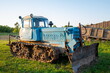 Rural farm field landscape. Soviet blue crawler bulldozer, front view
