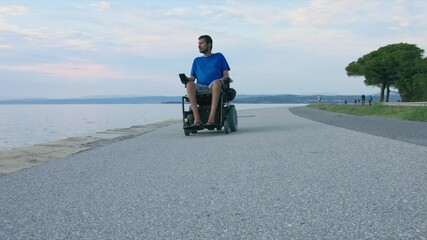 Wall Mural - Man on wheelchair near sea looking at sunset.