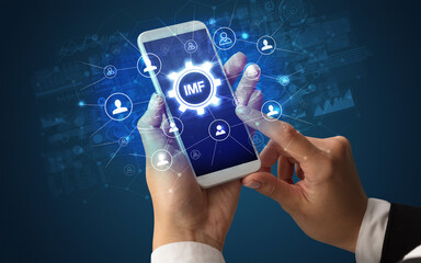 Female hand holding smartphone with IMF abbreviation, modern technology concept