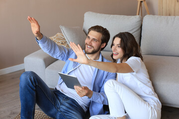 Happy couple sitting and planning new home decoration at home with a tablet, renovation and interior design for new house