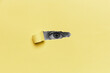 Image of human eye looking through hole in yellow paper sheet