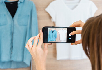 Woman taking photo of denim shirt white basic t-shirt on smartphone