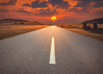 Wall Mural - Open highway in mountain range towards the sunset