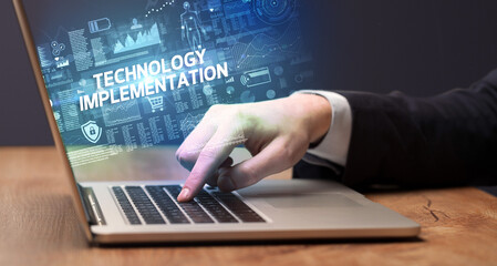 businessman working on laptop with technology implementation inscription, cyber technology concept