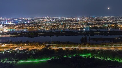 Wall Mural - Aerial panoramic view over Vienna city with skyscrapers, highway intersection, historic buildings and a riverside promenade night timelapse in Austria. Illuminated skyline from Danube Tower viewpoint