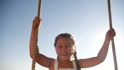 little girl kid swinging on a wooden swing on a tree in the park. happy family kid dream concept. li