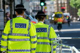 Fototapeta Londyn - Two Female British Police Officers walking down the street wearing fluorescent jackets
