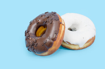 Two delicious donuts with black and white chocolate icing isolated on a blue background.