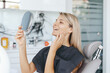 © diignat - Young woman patient is looking in the mirror and admires her new smile after dental treatment in the dentistry clinic.