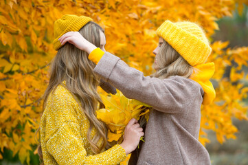 Friends enjoy an autumn day in the Park. Young happy women with yellow autumn leaves