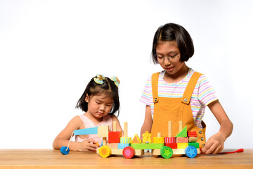 asian two sisters kids playing together on a wooden table with white background. skill of children, 