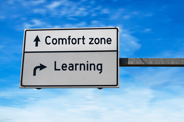 Road sign with words comfort zone and learning. White two street signs with arrow on metal pole. Directional road, Crossroads Road Sign, Two Arrow. Blue sky background