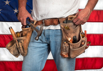 Closeup carpenter wearing worn out old, leather toolbelt with hand tools in front of American flag, construction, american pride, union labor, laborer, america, labor, worker, man, portrait