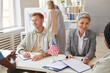 © Seventyfour - High angle portrait of multi-ethnic group of people voting at polling station decorated with American flags, copy space