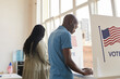 © Seventyfour - Back view portrait of young African-American people standing in voting booth and thinking, copy space