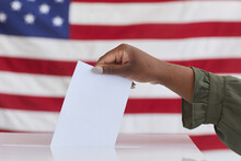 Side View Close Up Of Unrecognizable African-American Woman Putting Vote In Ballot Box Against American Flag Background, Copy Space