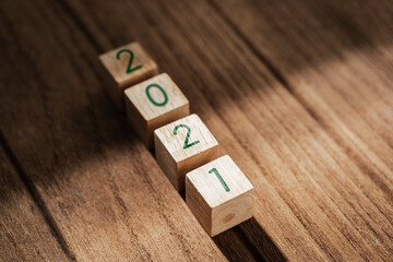 Aufkleber - 2021 happy new year on wood block on wood table and concrete wall with sunlight from window.hope new year concept