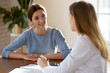 © fizkes - Smiling young woman listening to doctor therapist at meeting, sitting at work table in hospital, physician gp consulting patient about checkup results, giving recommendations at medical appointment