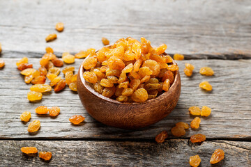 Wall Mural - Golden dried raisins in wooden bowl on a wooden table.