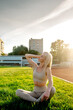 © Maria - Beautiful young blonde woman in sportswear sits on the grass in the stadium before training