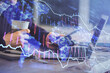 © peshkova - Double exposure of man's hands holding and using a phone and financial graph drawing. Analysis concept.
