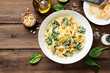 Pasta fettuccine with spinach  in creamy cheese sauce on a  wooden background.