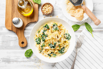 Pasta fettuccine with spinach  in creamy cheese sauce on a white wooden background.