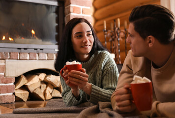 Canvas Print - Lovely couple with sweet cocoa near fireplace indoors