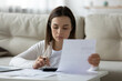 © fizkes - Head shot focused young lady holding banking mortgage payment notification, managing household budget alone at home. Serious woman calculating incomes outcomes earnings expenditures indoors.
