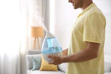 Canvas Print - Man with modern air humidifier at home, closeup