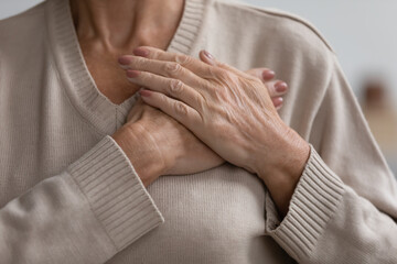 Close up cropped image hopeful grateful mature senior woman keeping hands on chest, mindful middle aged female thanking god and faith, feeling love, gratitude, appreciation, making wish