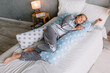 Pregnant girl sleeping in bed with maternity pillow