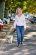 © JENOCHE - Elderly woman walking with a dog outdoors