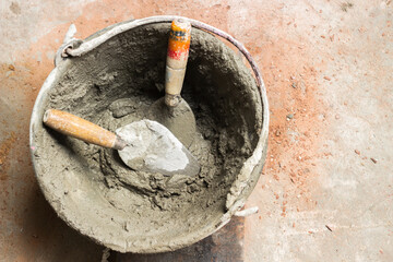 Wet cement mixed in tank with trowel at construction site.