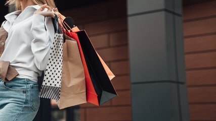 Close up portrait of european lady hold hand colorful bags woman after shopping in white shirt jeans retail store near mall on the street sales black friday season bokeh background