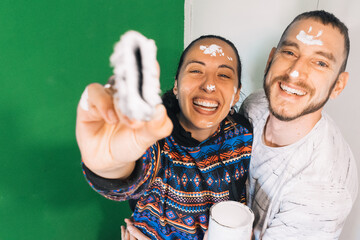 Lovely couple smiling after painting a room in their new home. Man and woman smiling painting a house. Young people smiling