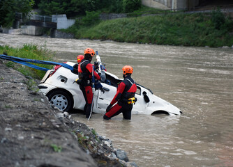 Firefighters and divers recover a driver's car that ended up in a lake or river after a terrible accident.	