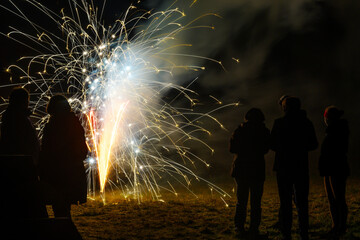 Sparking New Year fireworks fountain and people as silhouettes are standing around in the dark to celebrate the new year at midnight, copy space