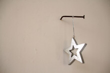 Silver Christmas Star Hanging On A String On A Long Rusty Nail In The Wall, Christmas Concept, Waiting For The Holiday