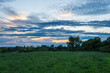 © Uniqueton - Stunning sky with the sunset peaking through the clouds over a hill with green trees in a park at Vienna Austria