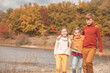 © Вероника Зеленина - Preteen kids, boy and twin girls walking in fall park with lake.  Friends wearing warm knit sweaters