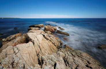 Wall Mural - Rocks and slow motion ocean wave at Rye Harbor State Park, Portsmouth NH, USA. The park affords scenic views of the Atlantic Ocean, the Isles of Shoals, and Rye Harbor, also called Ragged Neck.